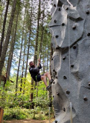 man repelling from rock climbing wall in the woods