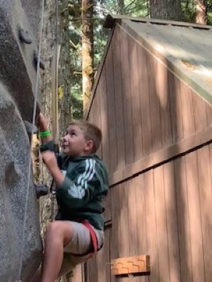 male child climbing rock wall