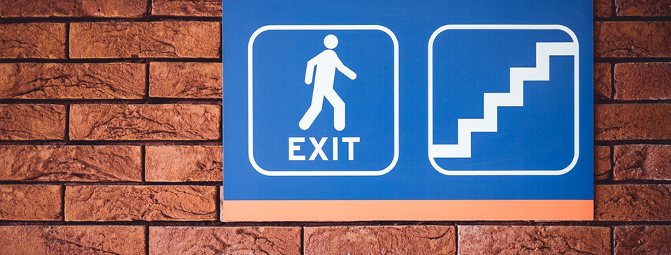 blue and white exit and stairs safety sign on brick wall